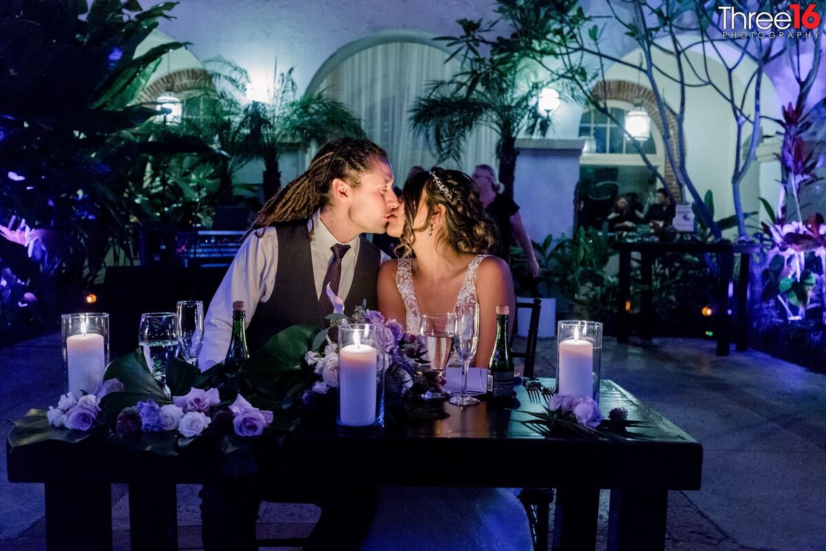 Bride and Groom share a romantic candlelit kiss during their wedding reception