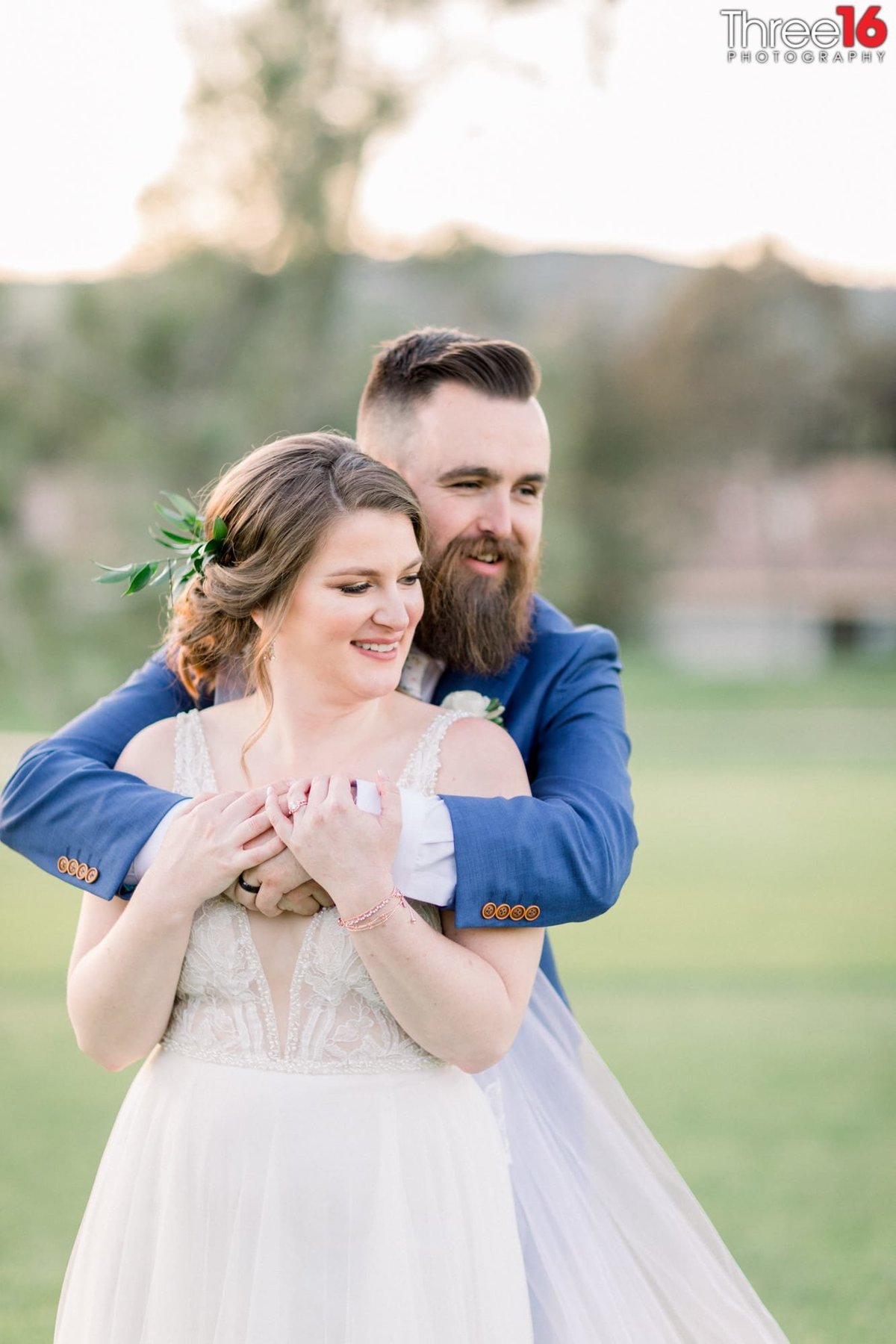 Groom fully embraces his Bride from behind during photo session