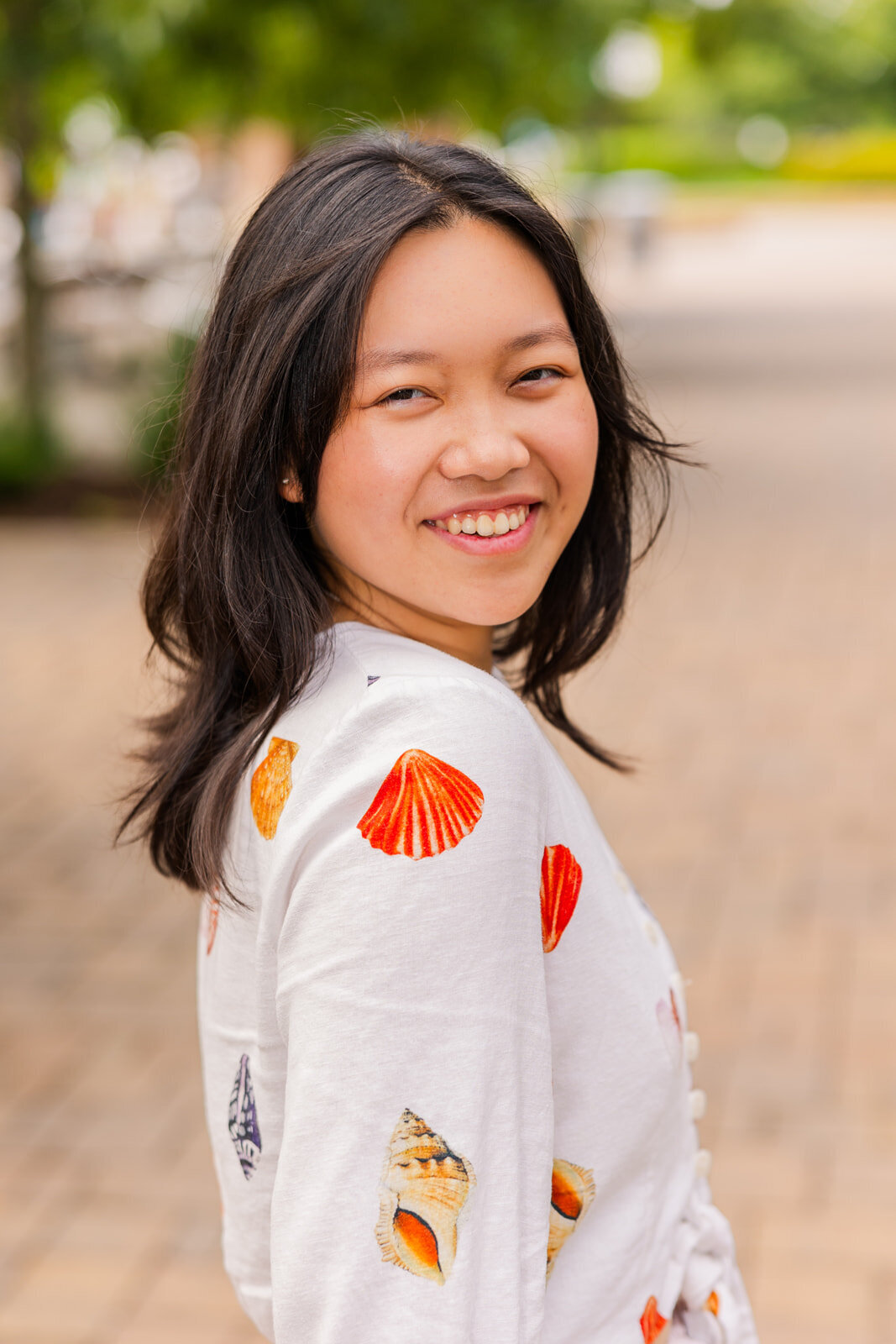 teenage girl wearing a shirt with patterns looking at the camera over the shoulder