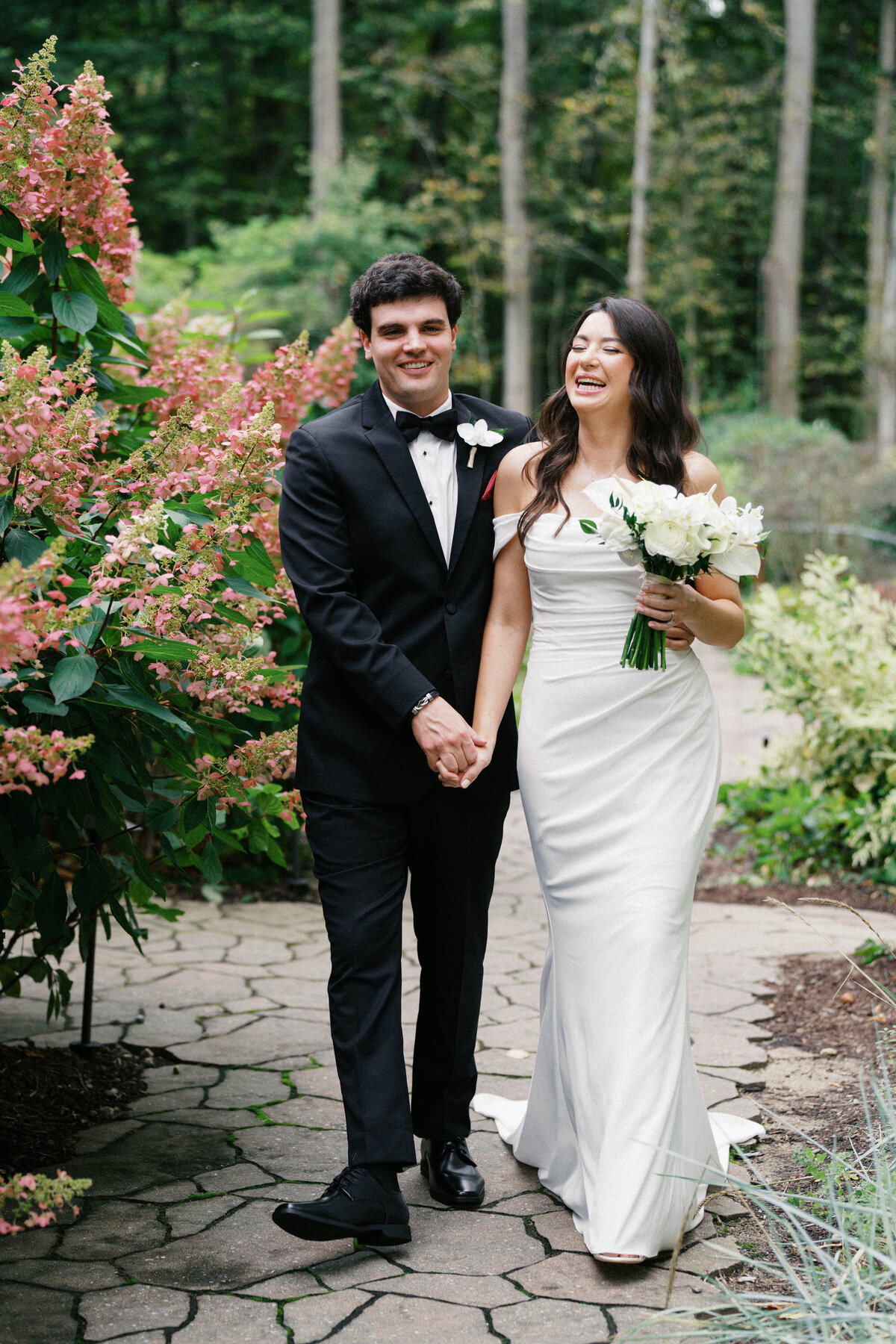 Bride and groom walking hand-in-hand through gardens at Sapphire Creek Winery

