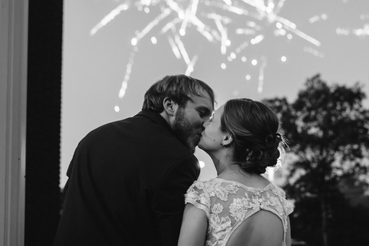Bride & groom kissing under fireworks after Mississippi wedding.