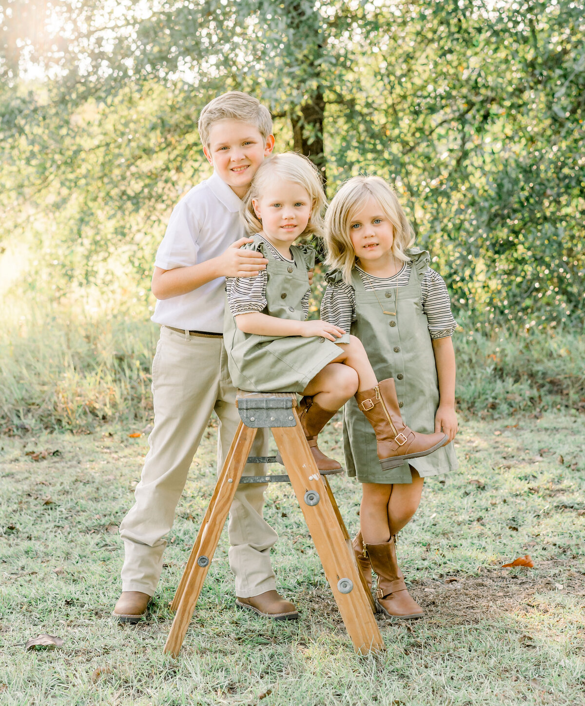 Brother hugging 2 sisters posing on ladder during christmas mini session