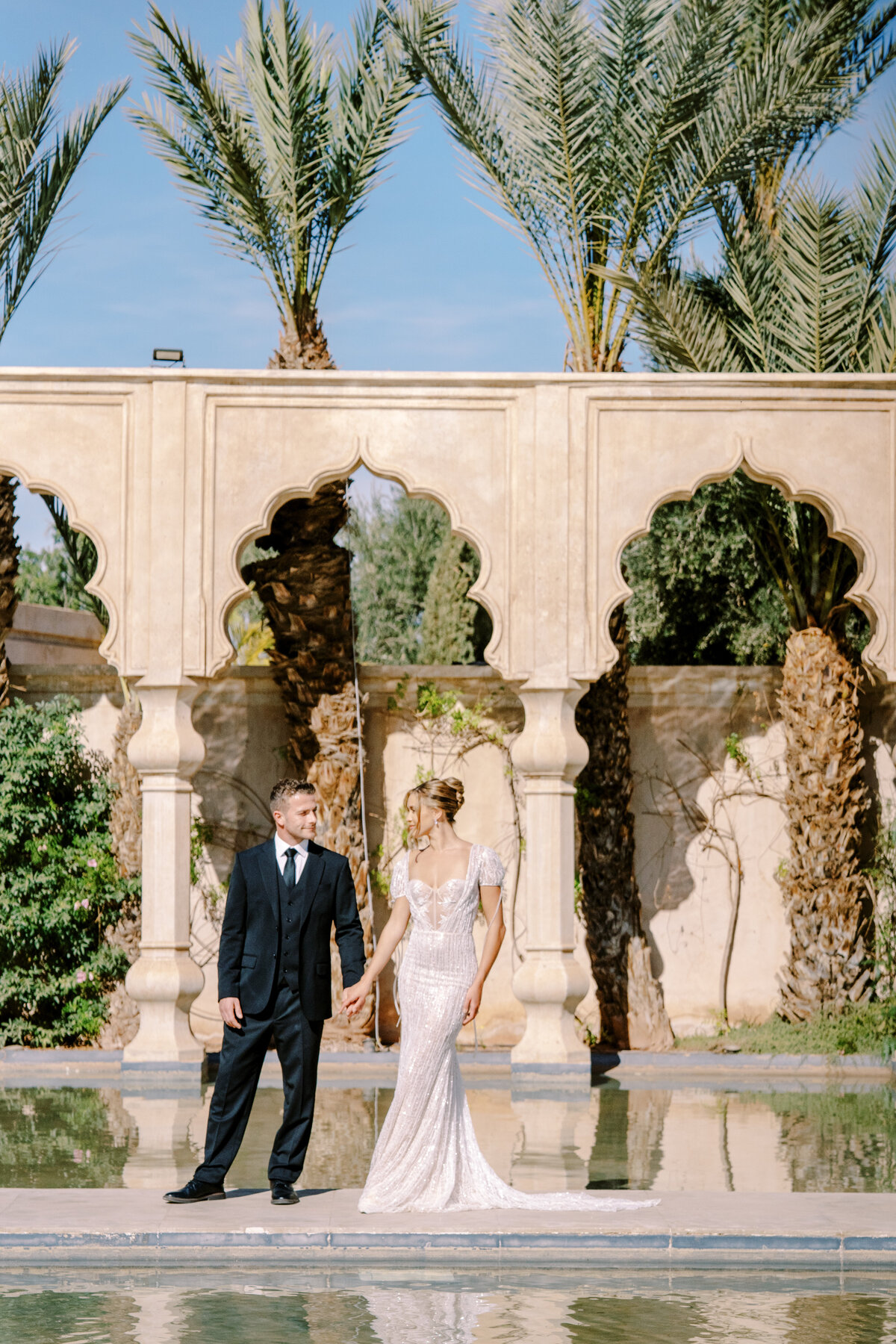 Bride in updo and short sleeved beaded wedding gown with bows and groom at Palais Namaskar Morocco for a destination wedding photographed by Italy photographer
