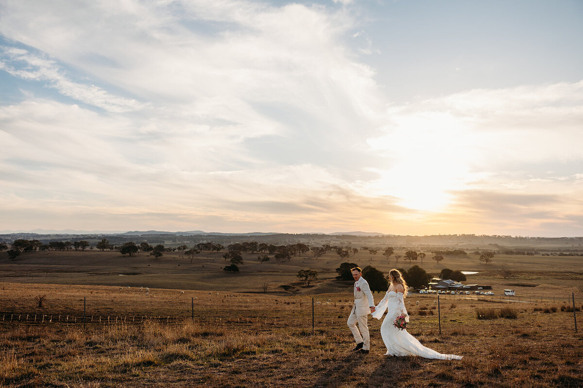 Bride and groom walking across hill during sunset photos on their wedding day at Petrichor Farm