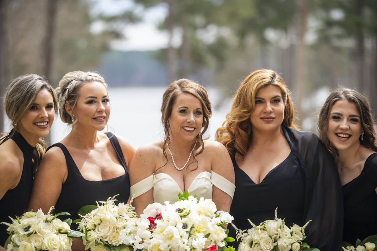 Bride standing with bridesmaids holding bouquets.