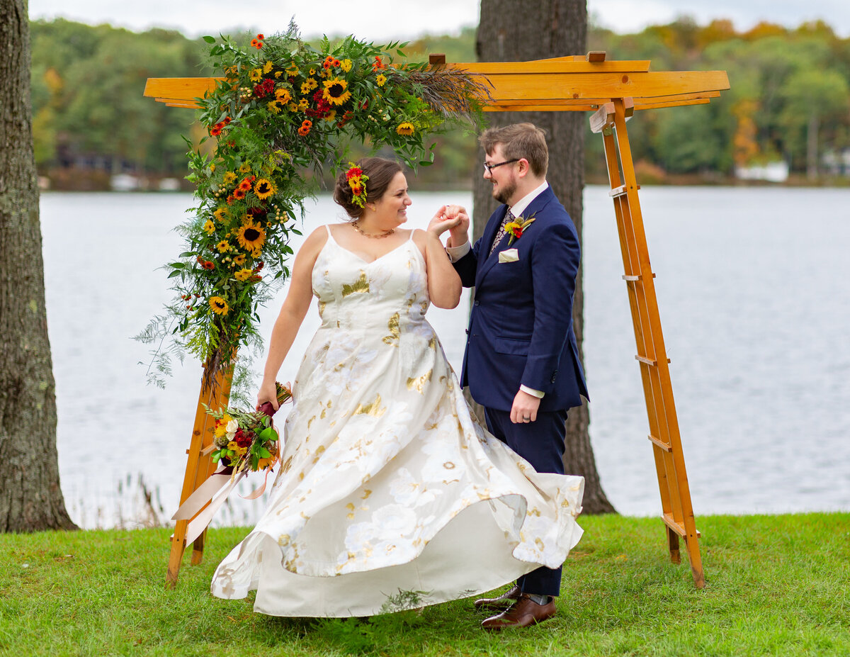 Wedding couple dancing in front of a small arch.