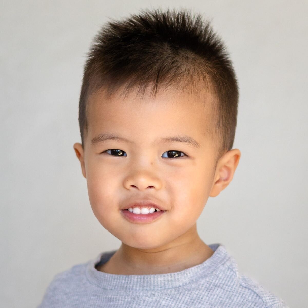 Happy preschool boy smiling under soft natural light with beige white backdrop in Bay Area School Photography portrait – Ellobelle Photography