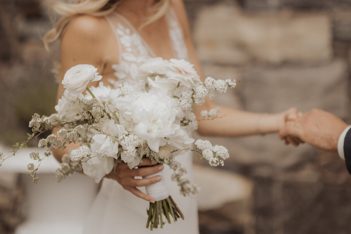A bride at Chateau Ste-Agnes holds an elegant bouquet of white flowers.