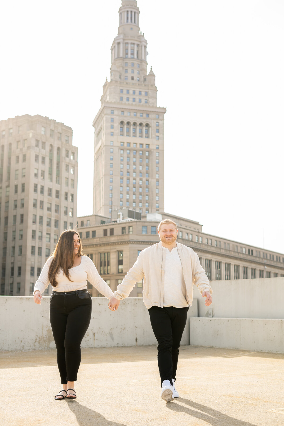 couple walking hand in hand during rooftop golden hour engagement session Cleveland