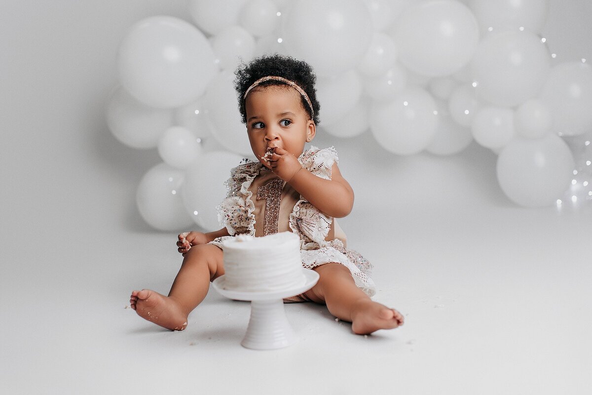 Baby wearing gold birthday crown during cake smash photo session
