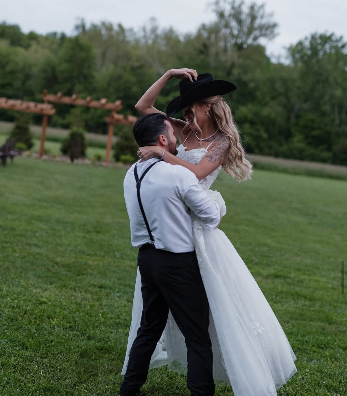 Groom carries bride while hugging her