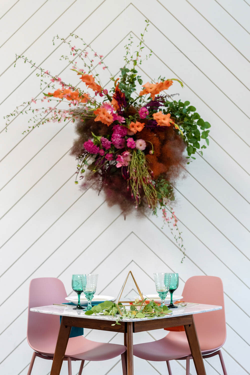 a pretty sweetheart table with colorful flowers and pink chairs
