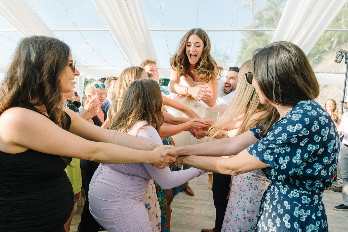 A fun bride being thrown in the air during a hora at a tented wedding in Muskoka