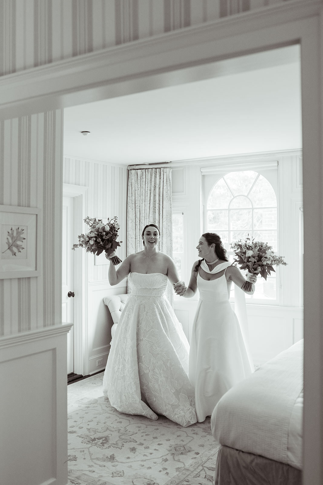 Two brides laughing while holding wedding bouquet