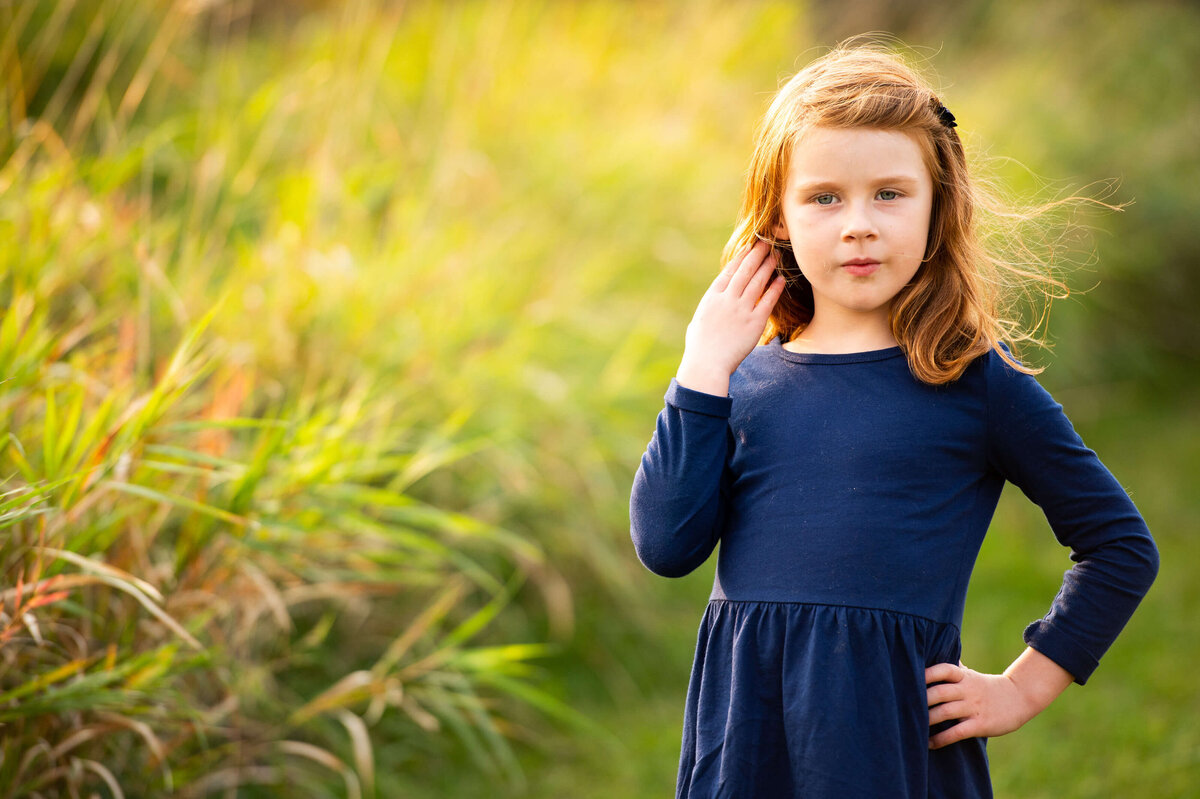 family photography in Ottawa showing a closeup of a young girl in a grassy field at sunset  golden hour