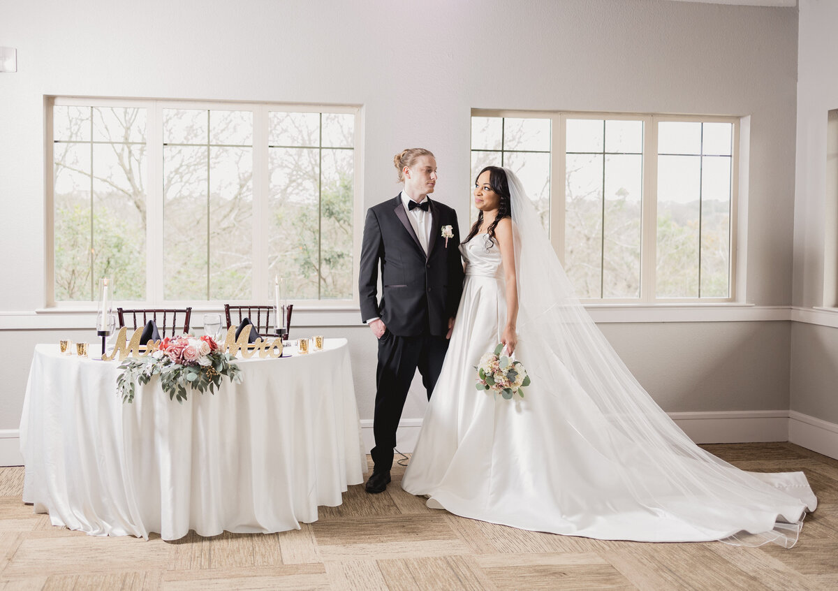 Bride and groom gazing at each other beside sweetheart table