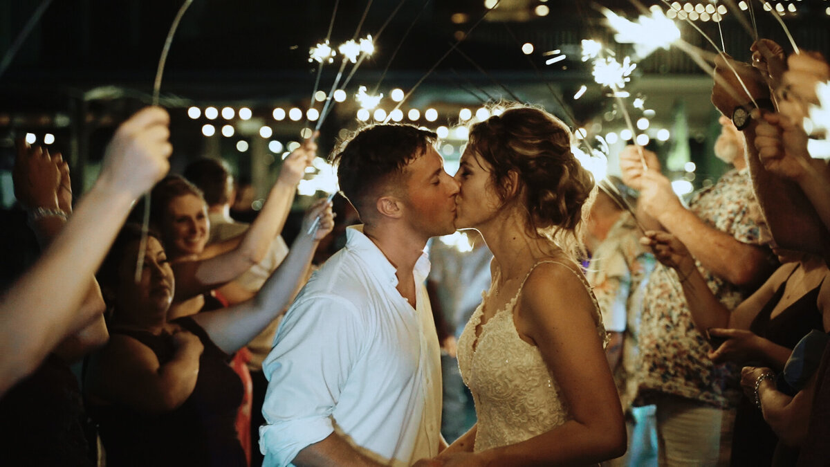 Couple kissing in front of a wedding sparkler send off.