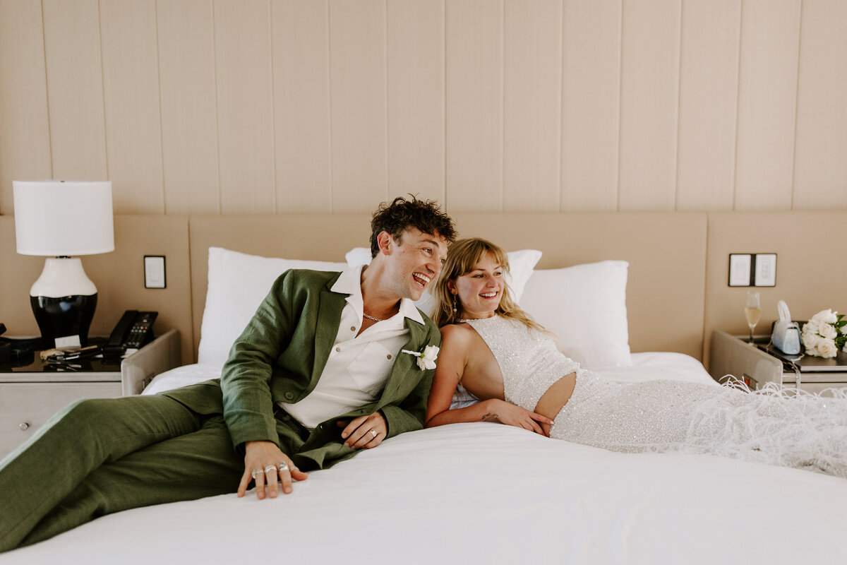 Partners lay in bed, laughing.