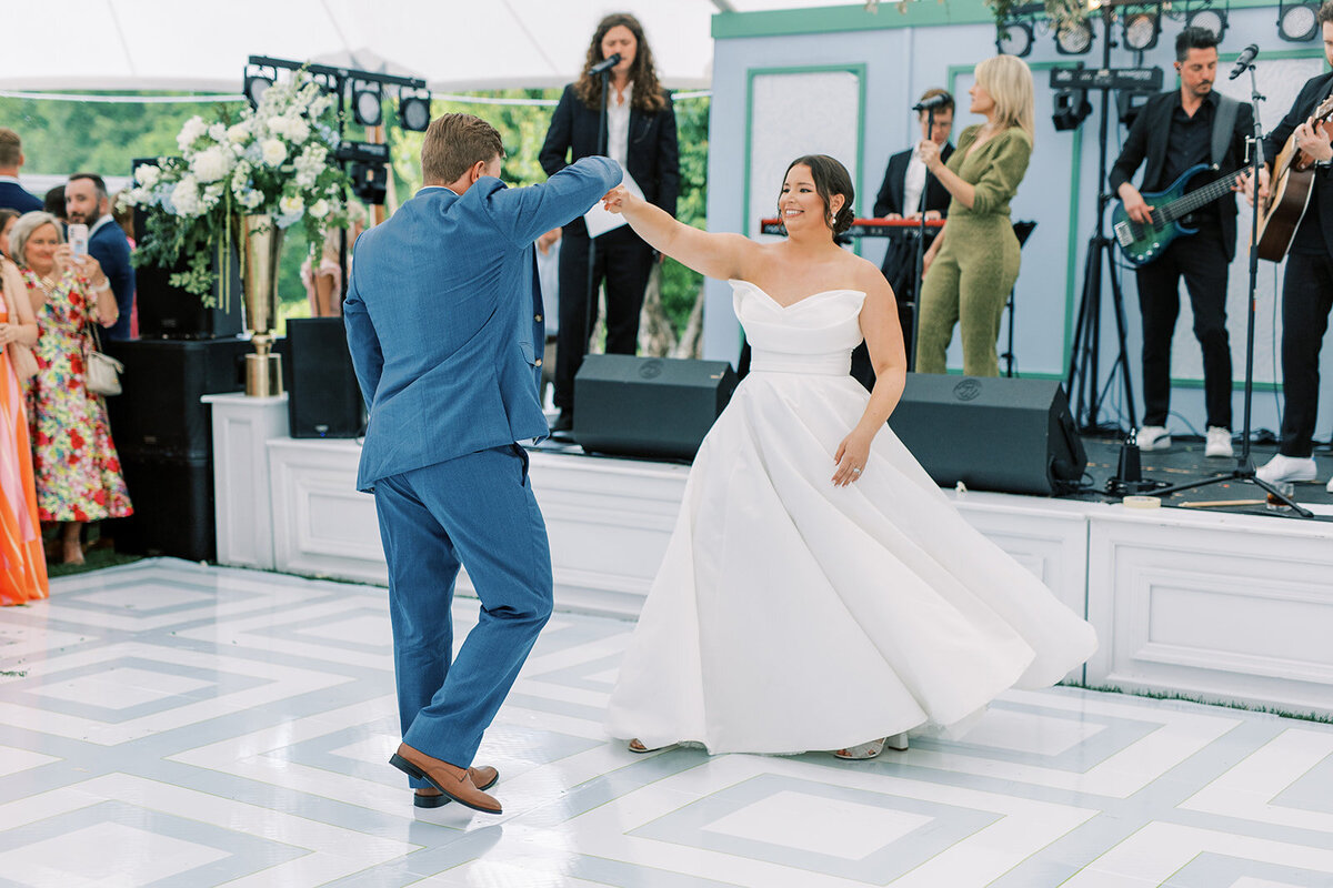 Bride and groom share their first dance under a sailcloth tent with a live band at Trillium Links & Lake Club in Cashiers, North Carolina.
