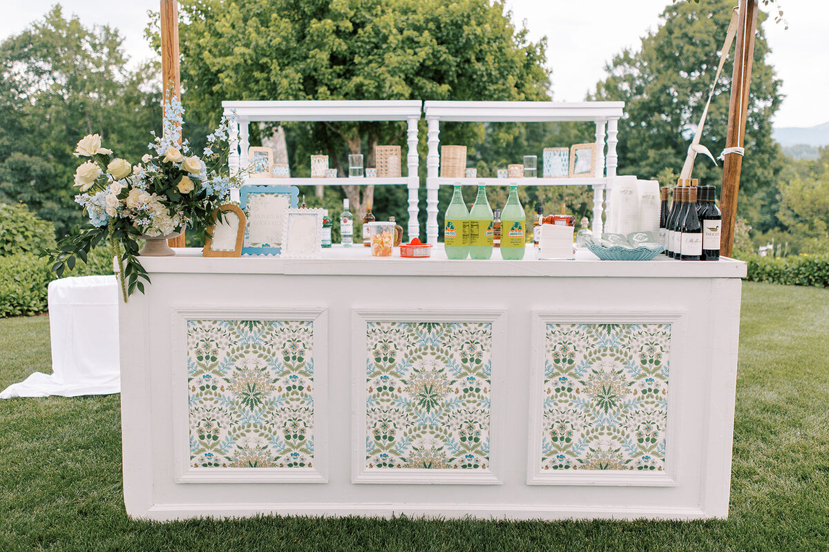 Custom wedding bar with blue and green patterned panels and floral arrangements at a Cashiers NC wedding.”
