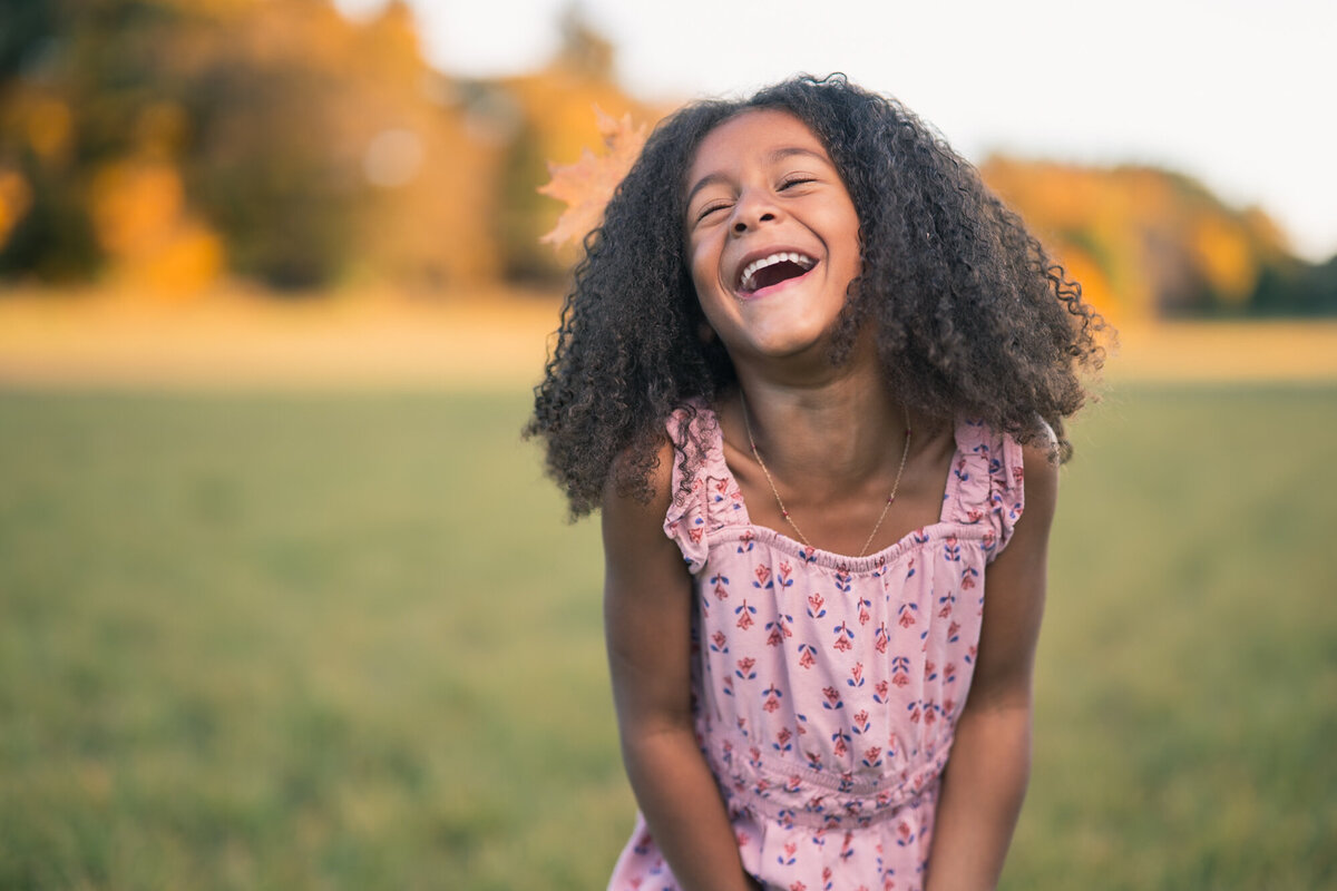 Girl laughing in new england farm field with fall colors