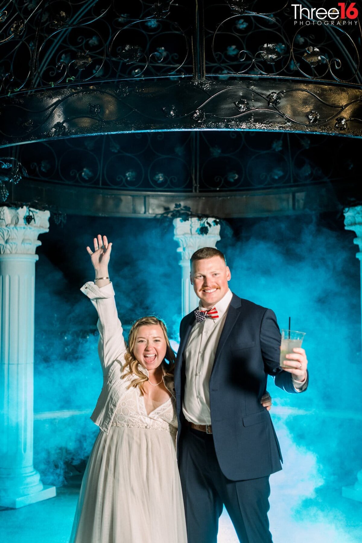 Bride and Groom celebrate to the photographer with blue mist behind them