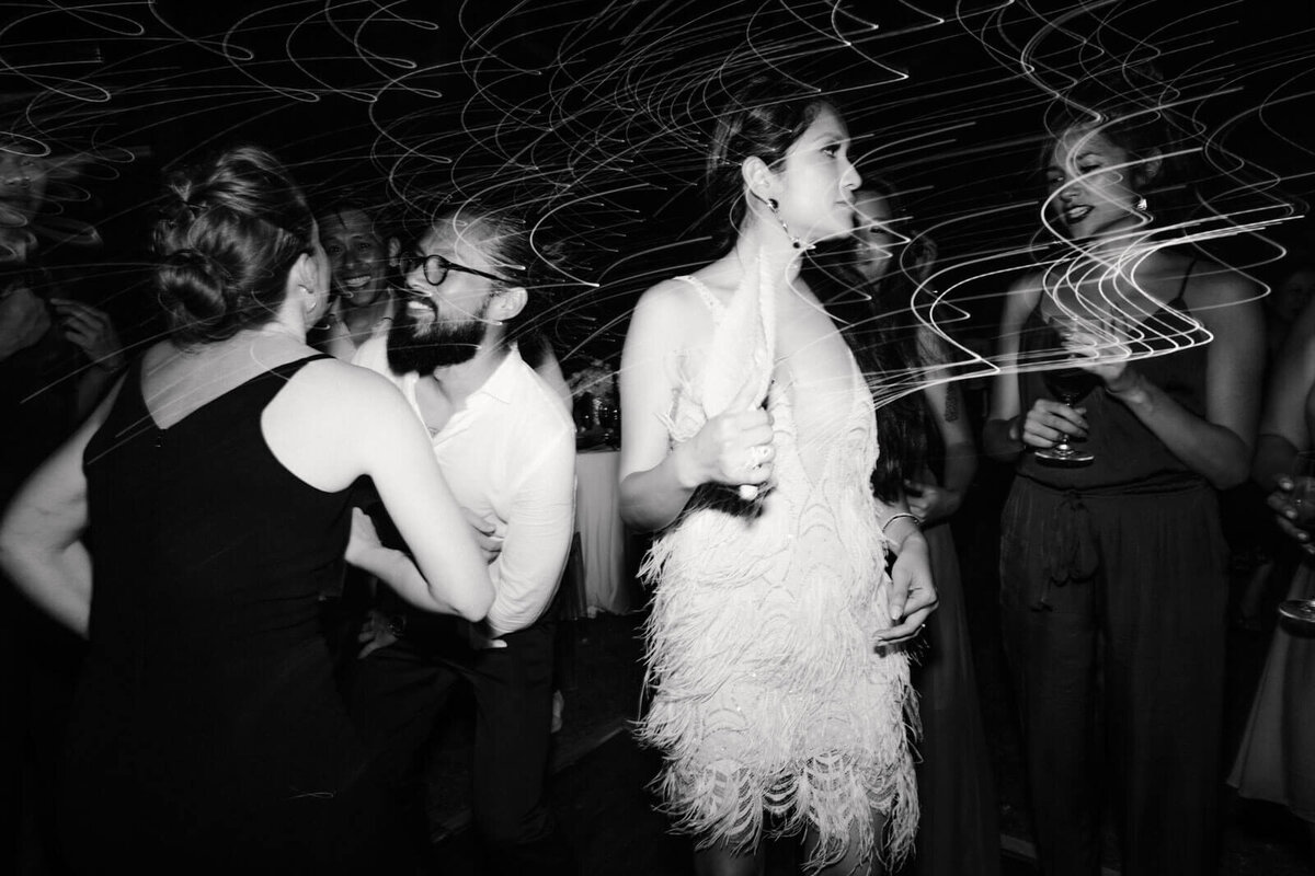 Black and white photo of the bride dancing with the guests in Khayangan Estate, Bali, Indonesia. Image by Jenny Fu Studio
