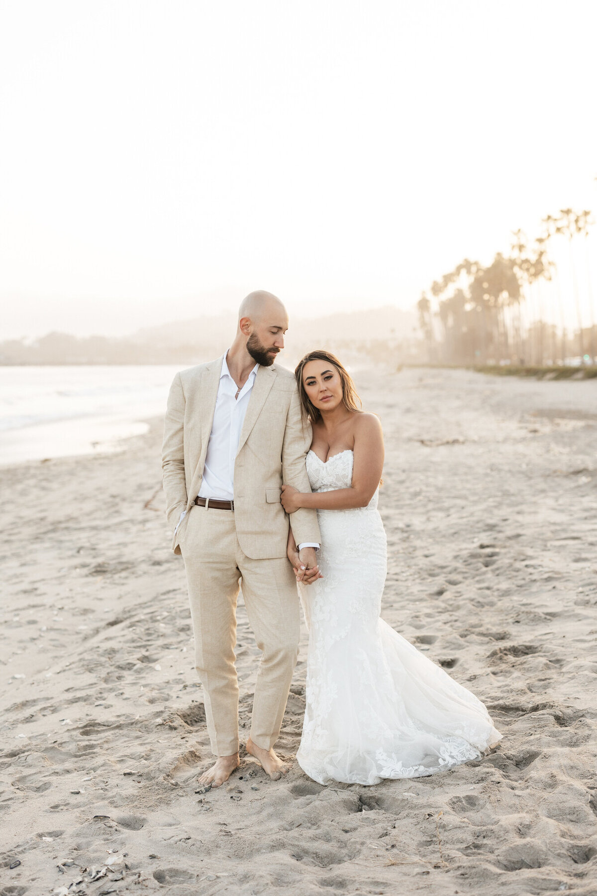 Bride and groom holding hands on beach during sunset at Hilton Beachfront Resort Santa Barbara