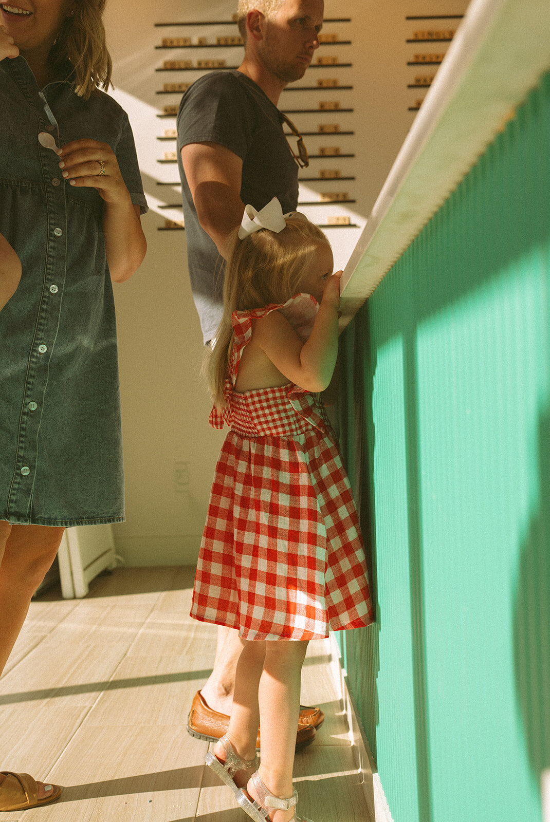 Young girl stretching to peek over the ice cream counter at a local shop during a documentary family session
