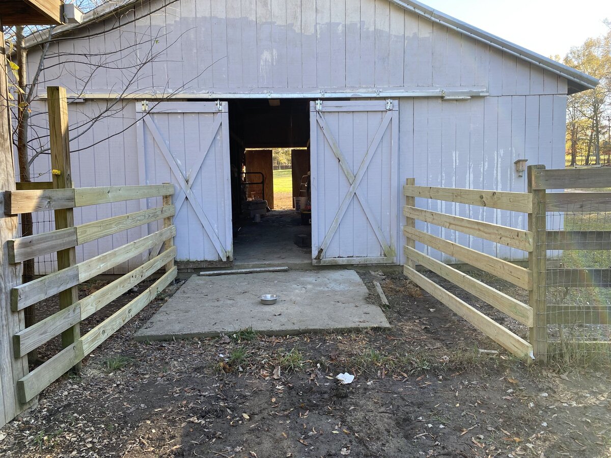 white-barn-with-doors-open-and-wooden-fencing