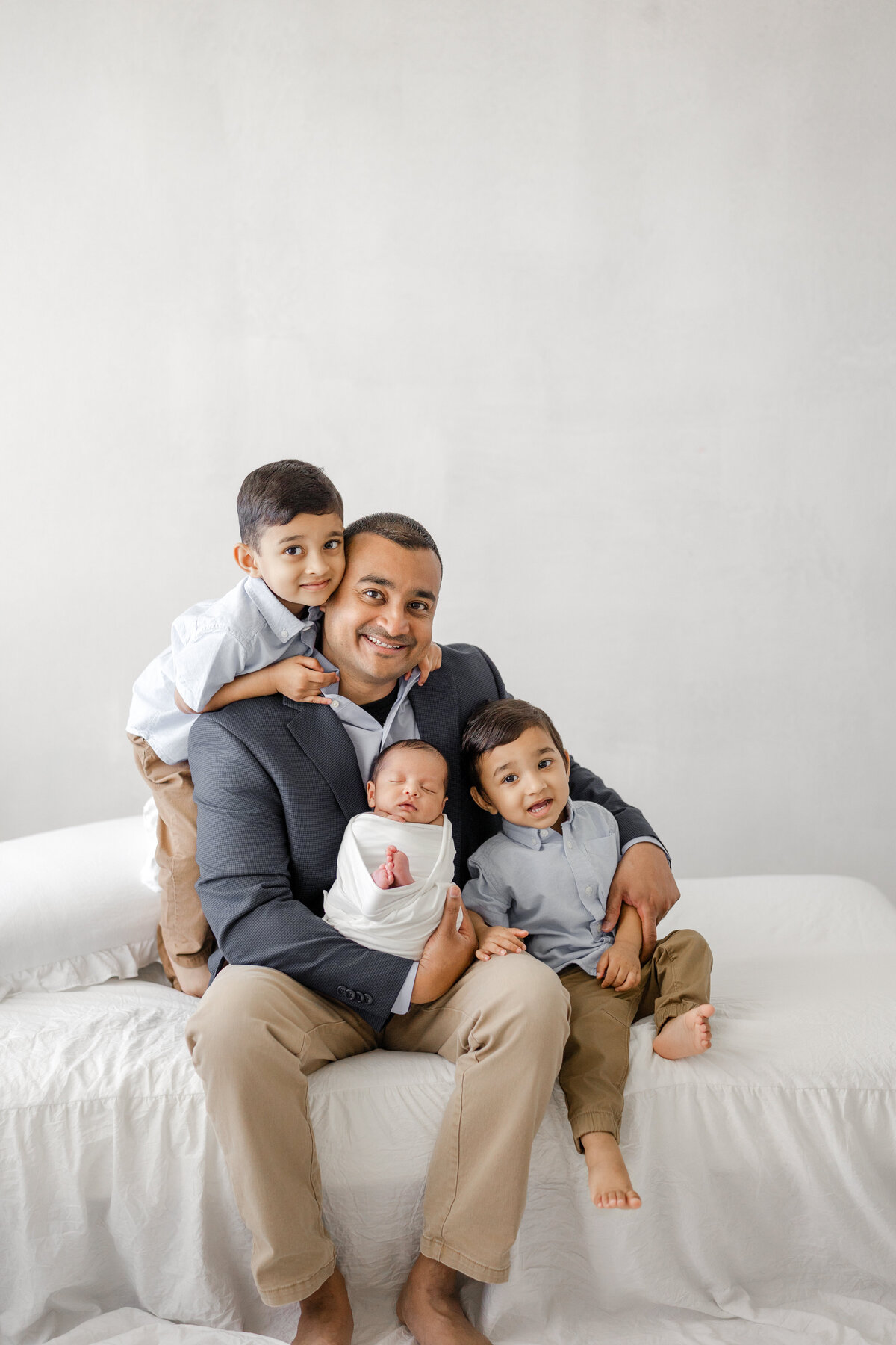 Elegant newborn family portrait in Tampa studio with father holding baby in soft natural light