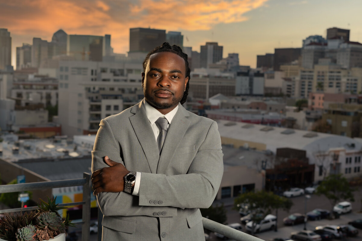 Black male real estate agent in gray suit with city in the background