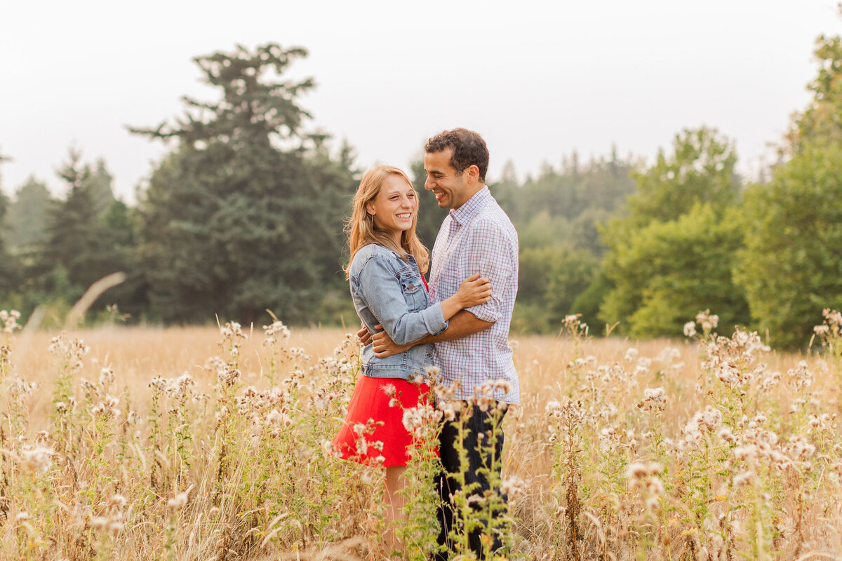 Happy relaxed couple in field of long grass at golden hour engagement session Discovery Park in Seattle WA photo by Joanna Monger Photography