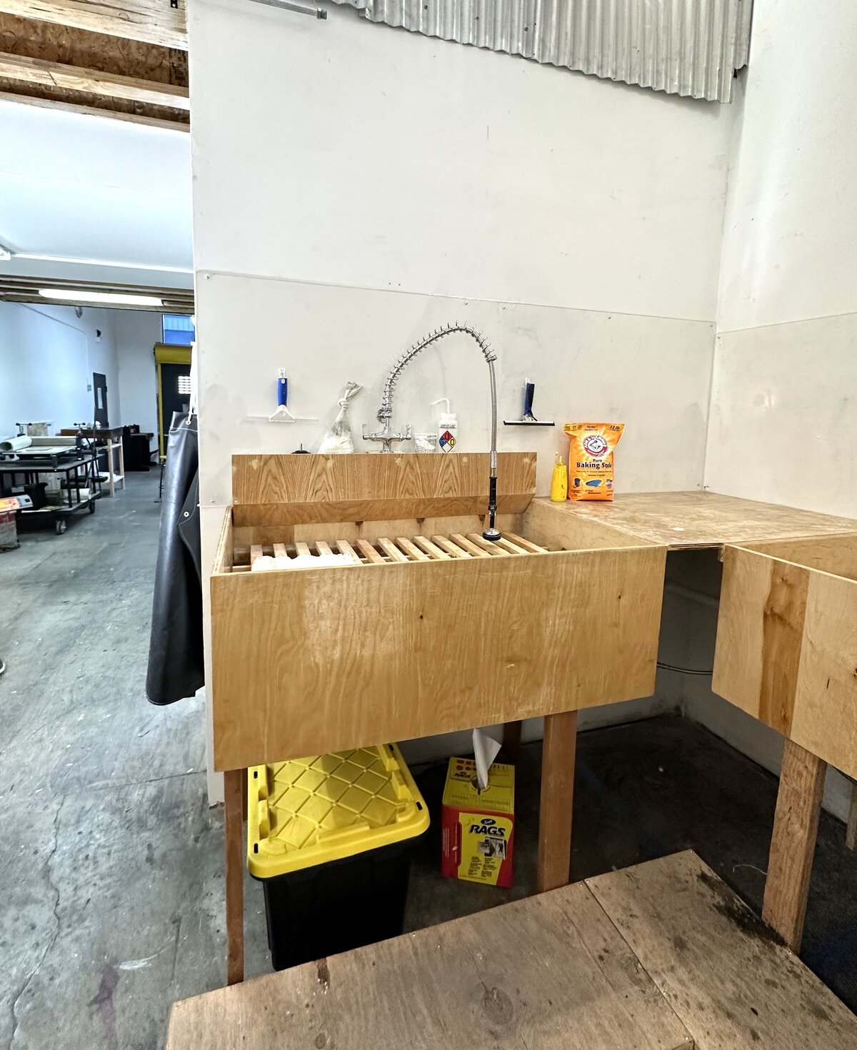 A specialized cleaning sink with wooden drying racks, located in a printmaking studio, for washing and preparing printmaking materials.