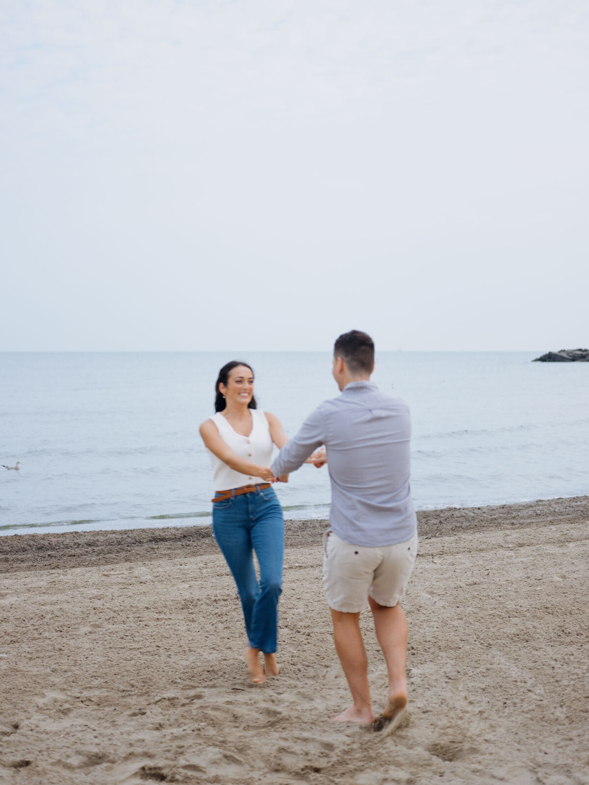 Loving couple twirling near the water during their Cleveland Lake Erie beach engagement.