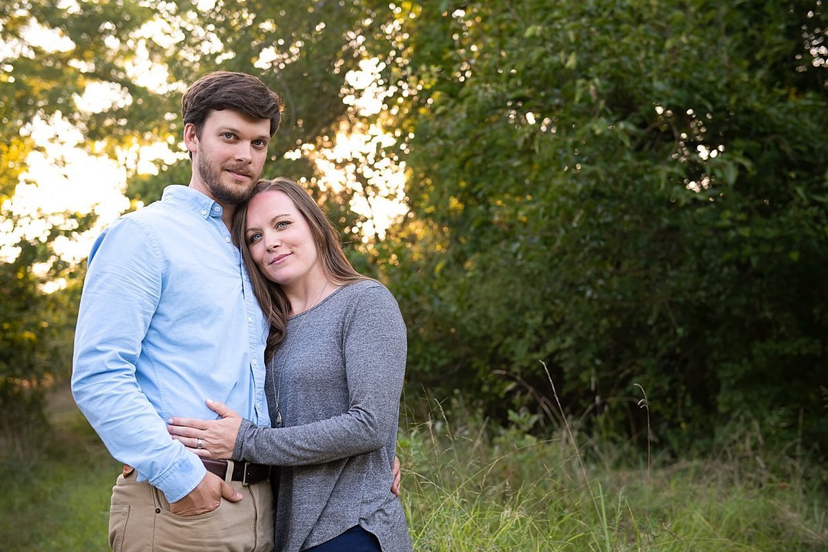 Engaged couple standing in a field of tall grasses at sunset during their engagement session in Pittsburgh, PA