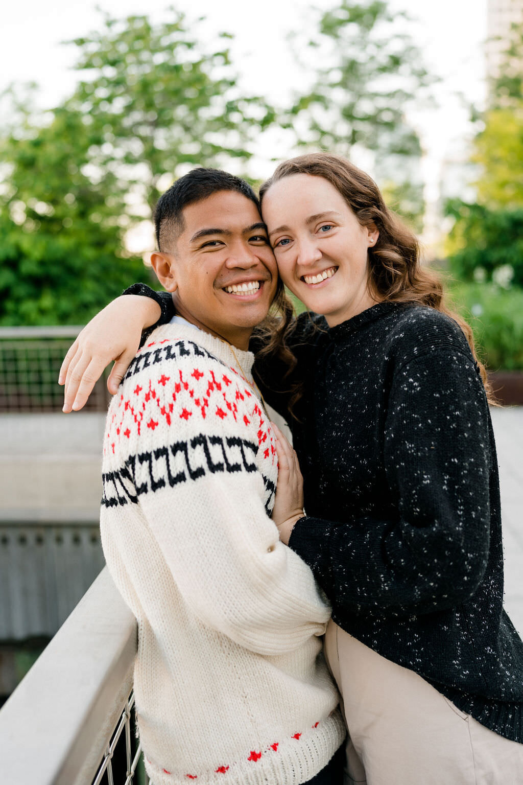 couple leaned up against each other along a railing with their heads touching as they smile