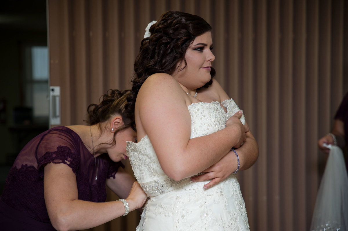 bride adjusts dress to zip