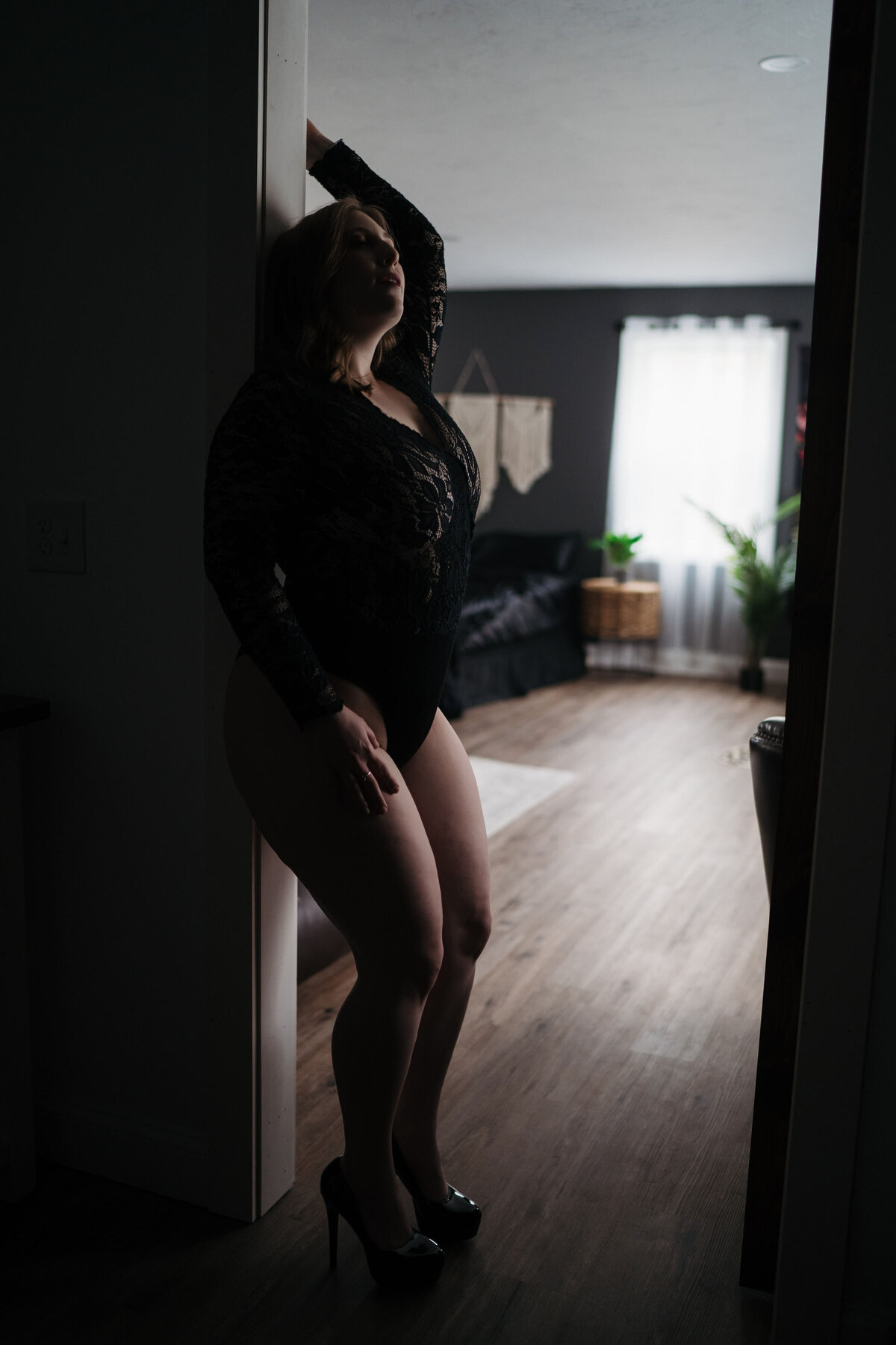 Woman wearing black lingerie standing in a door frame