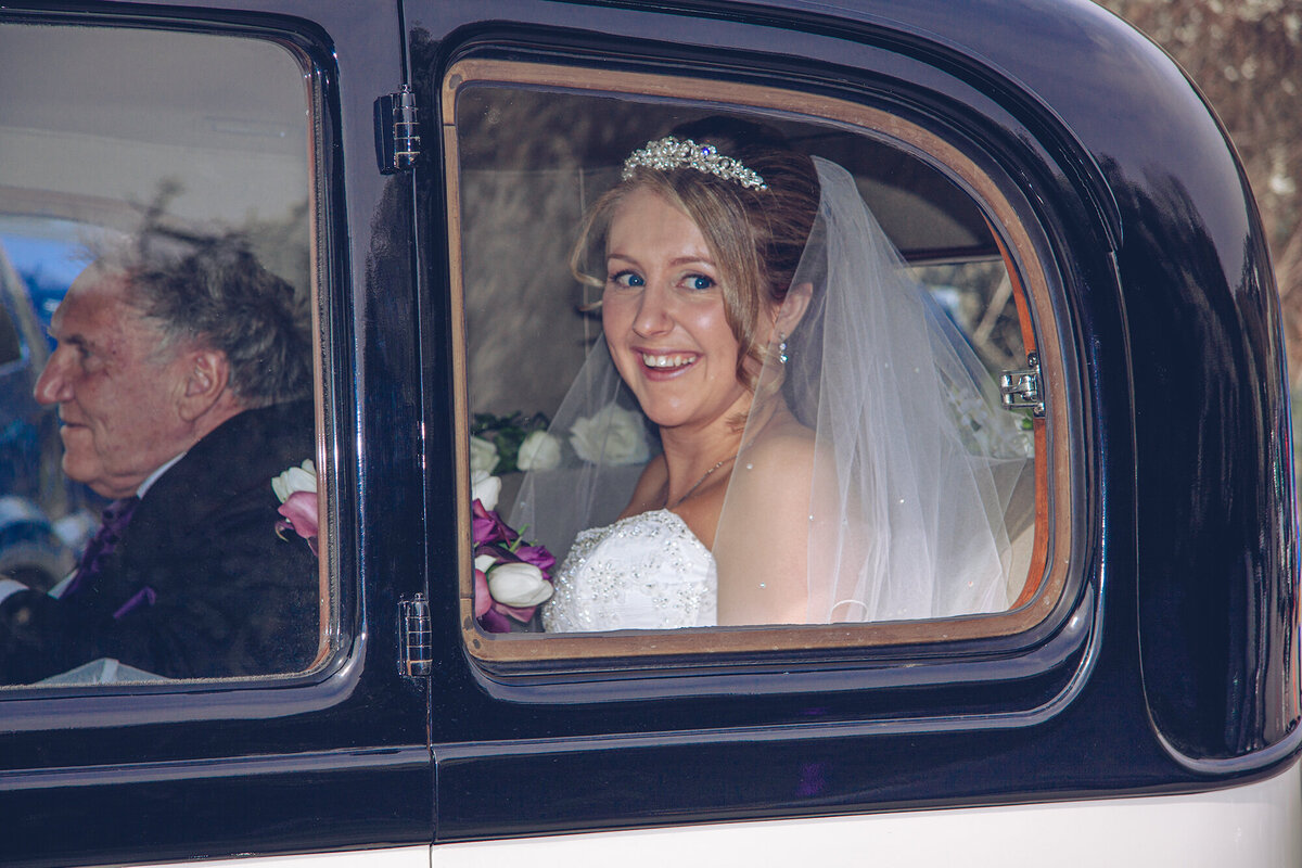 pro-story-photography_bride-looking-out-of-car-window_vintage-rolls-royce_wembury-church_wembury-bay_devon