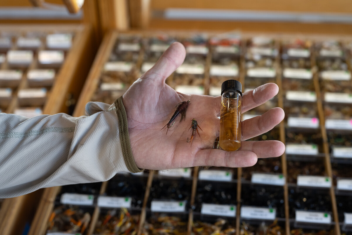 A branding photographer and product photographer in Denver takes a picture of a man's hand holding stages of flies for a fly tying business for their branding photos and denver branding photography session.
