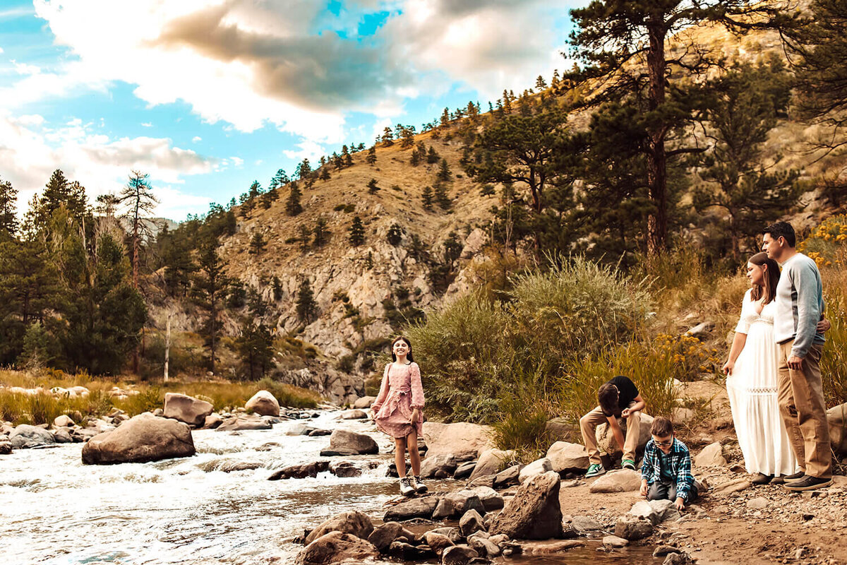 Mom and dad watching their 2 sons and daughter at a stream in the Loveland, Colorado mountains.