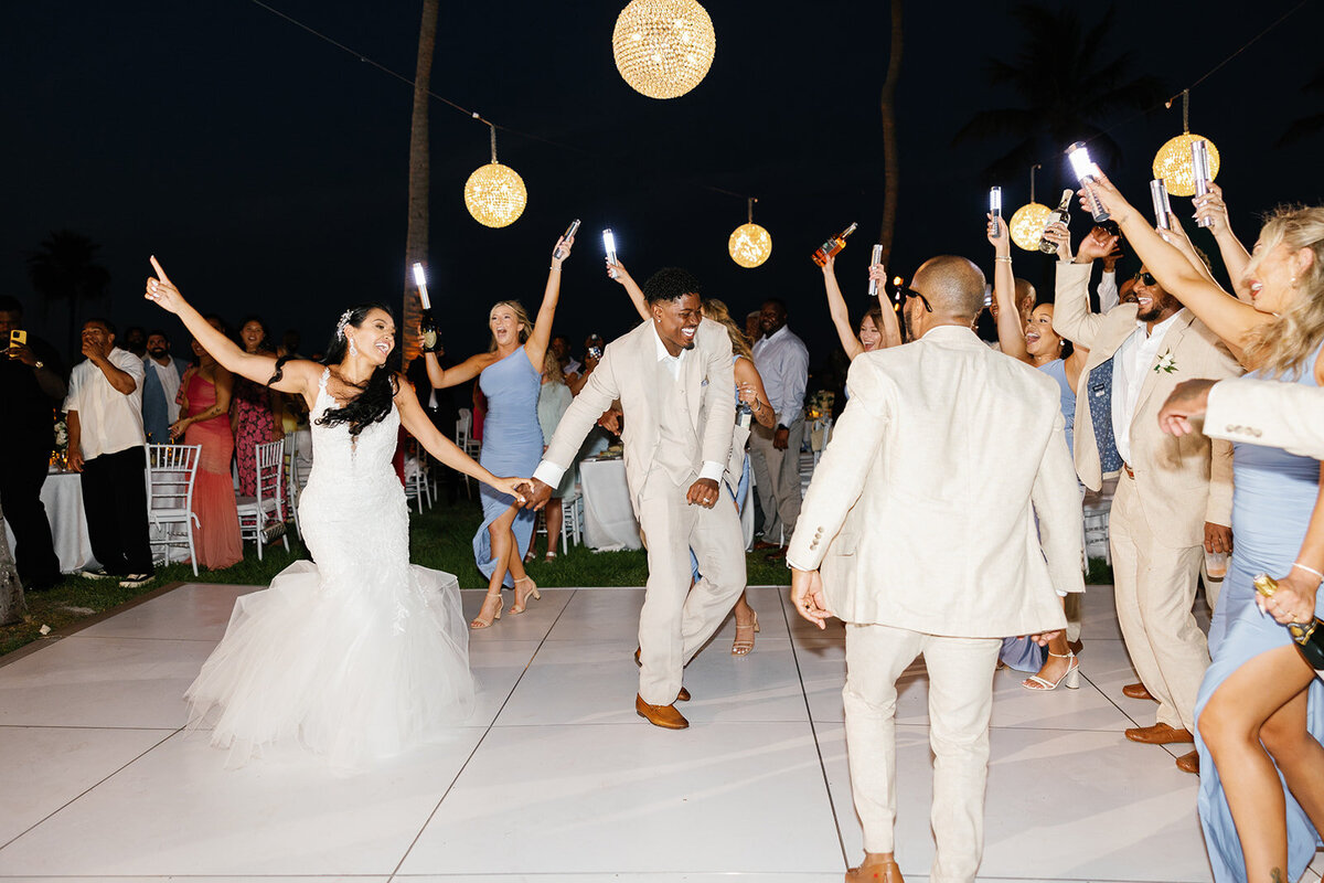 Andressa and Jonathan joyfully enter their wedding reception, dancing under the stars as their guests cheer at Table Key, Islamorada. Photography by Claudia Amalia Wedding Photography.