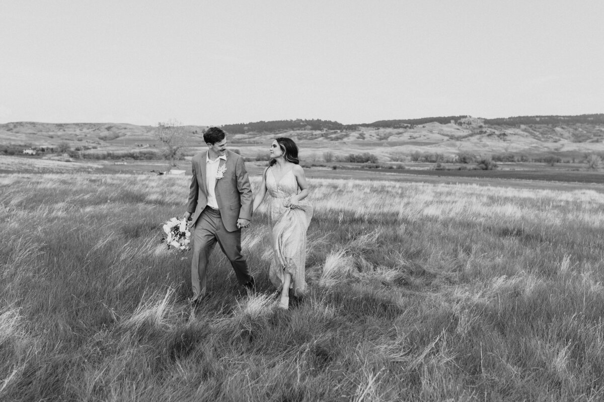 black and white image of  wedding couple walking in field