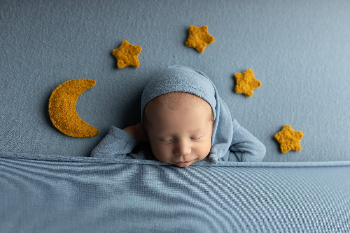 Newborn boy wrapped in blue with yellow felt moon and stars | DFW newborn photographer specializing in creative baby portraits