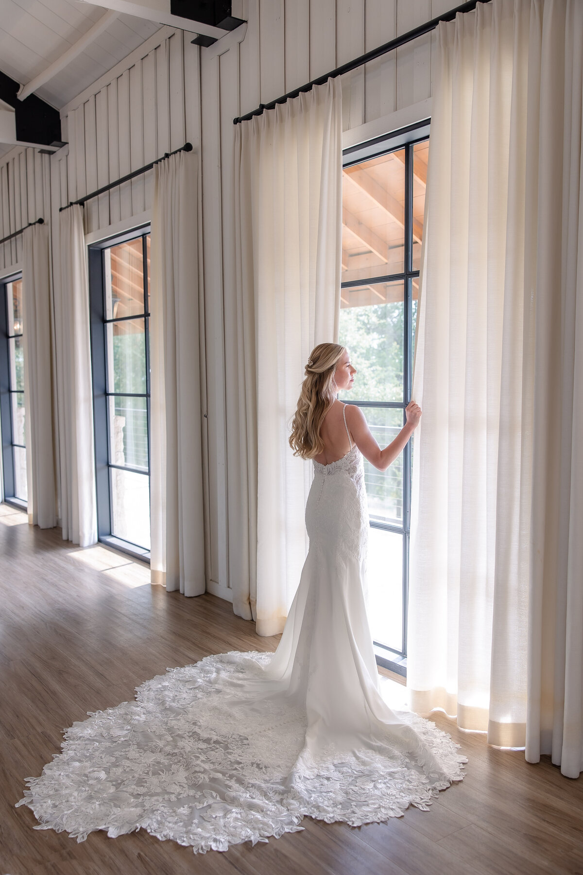 bride in flowing gown stands by floor to ceiling window at Milestone Georgetown wedding