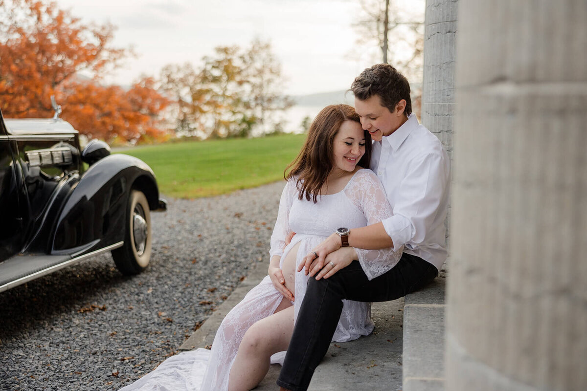 Couple sitting on steps outside historical building at Finger Lakes maternity session, NY