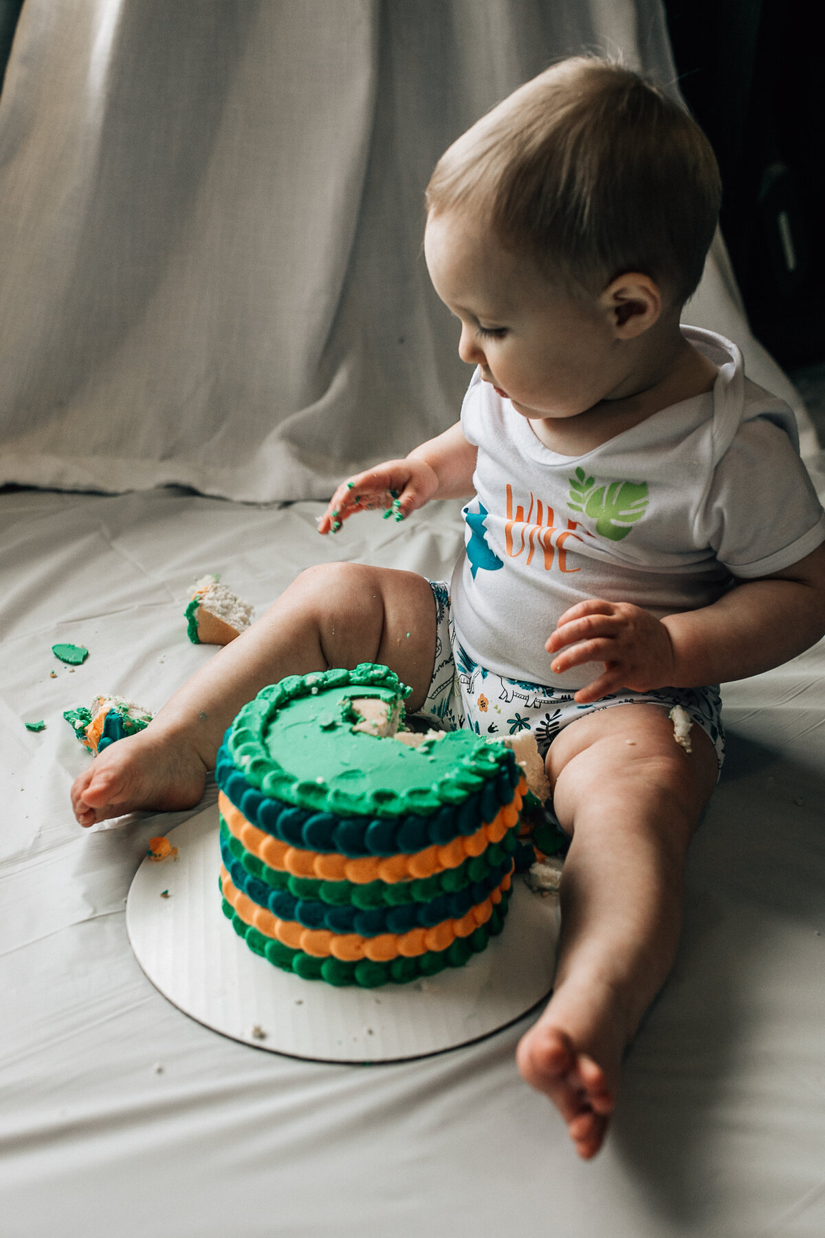 Baby sits on the floor with cake.
