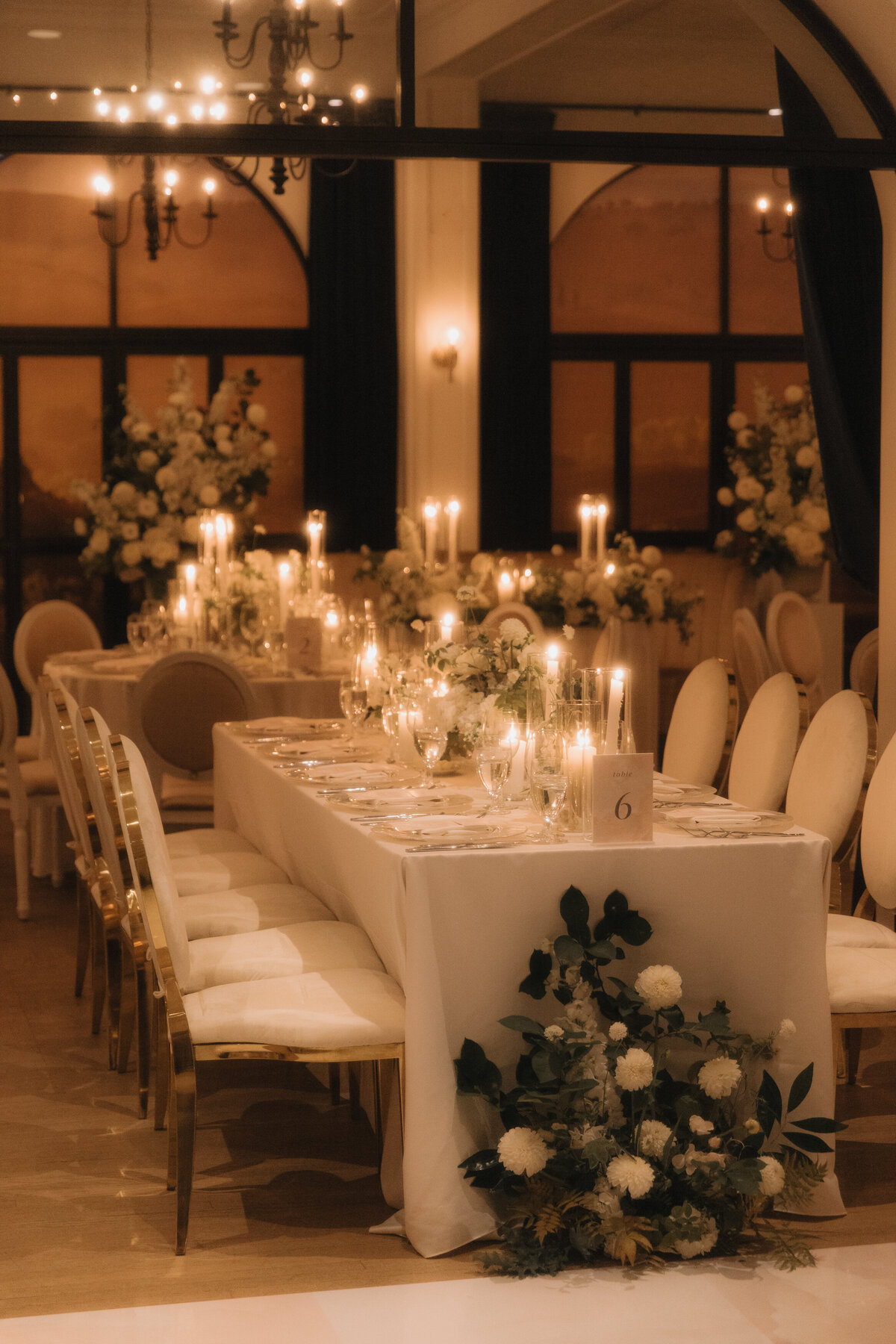 Elegant place settings at the Atwater Club decorated with cozy candles and lush arrangements of white flowers.