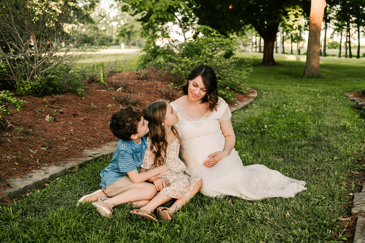 pregnant mom looking down at her 2 older children at Nathanial greene park in Springfield MO captured by Springfield MO newborn photographer Jessica Kennedy of The XO Photography